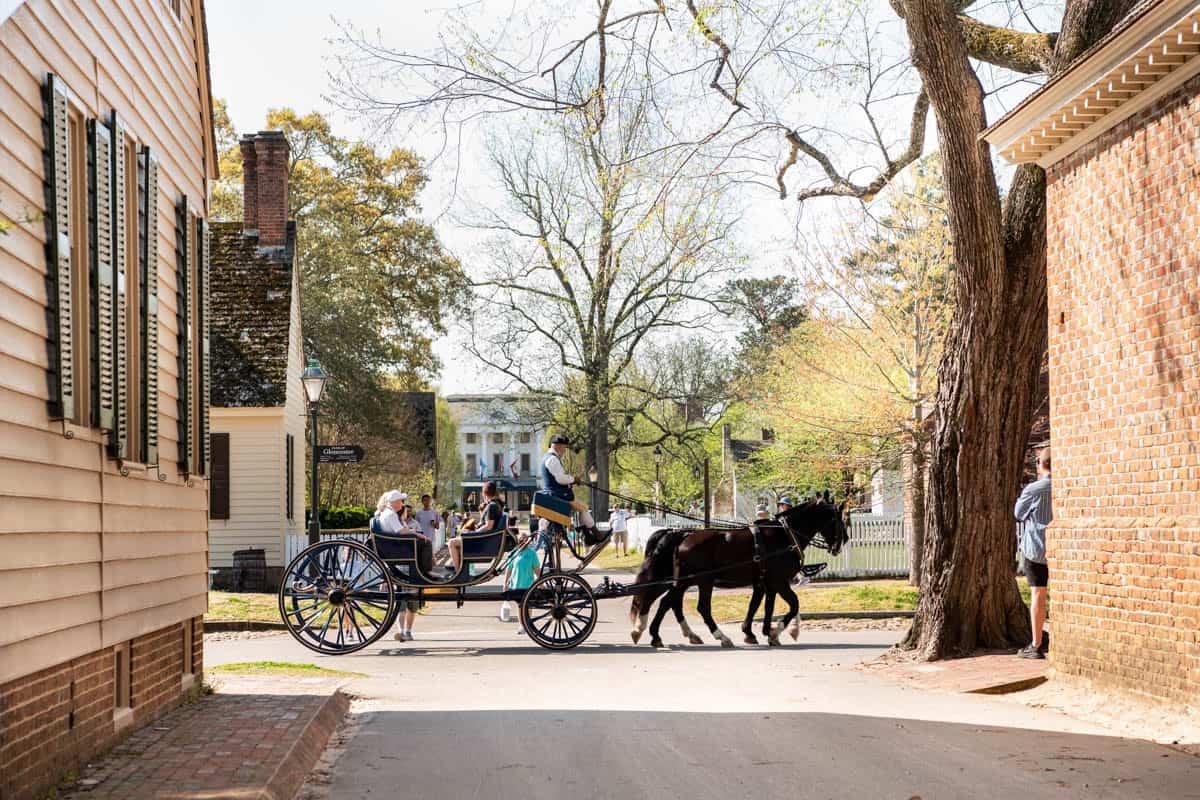 A horse-drawn carriage driving through the streets in Colonial Williamsburg.