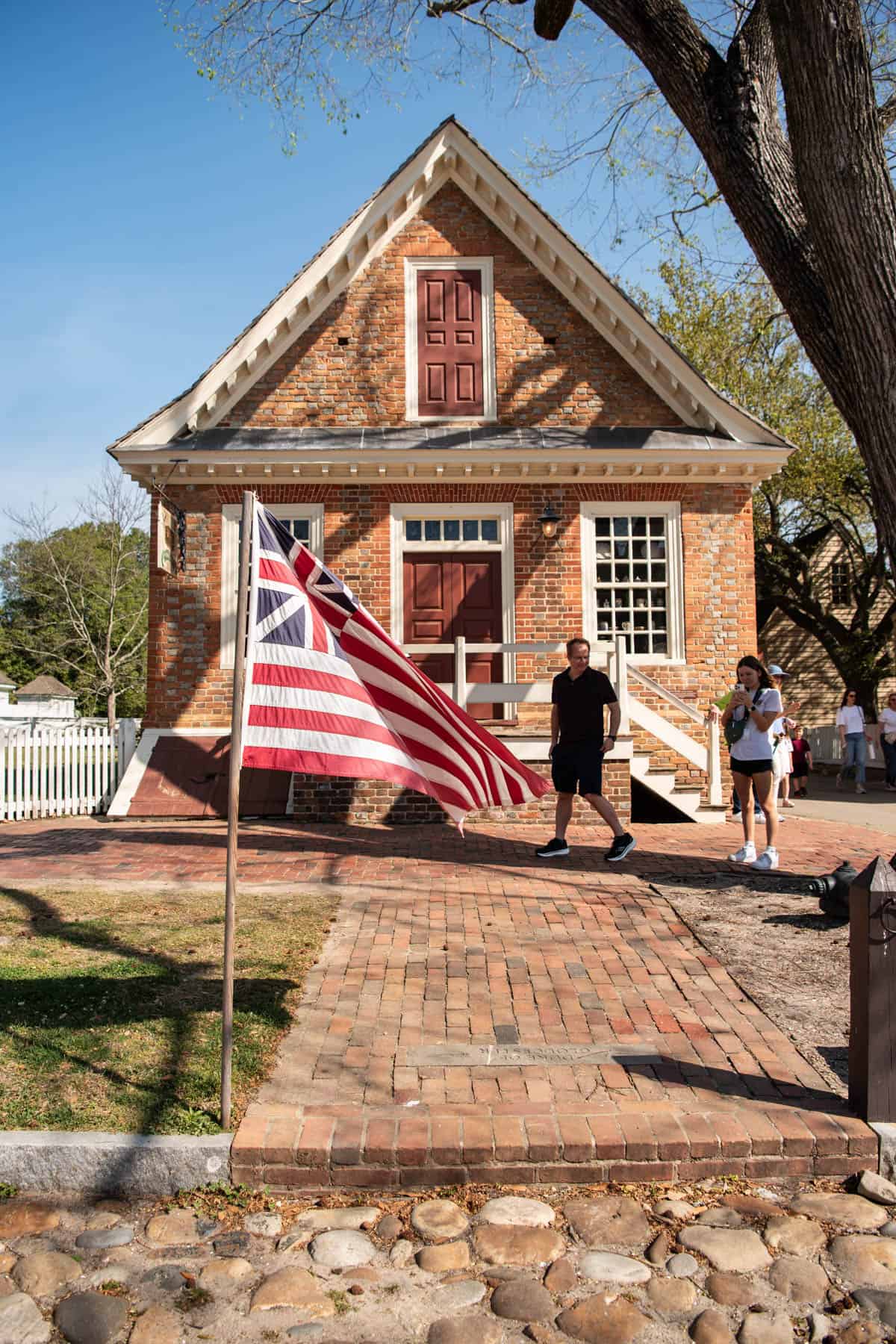 A revolutionary war flag flying in front of a building in Colonial Williamsburg.