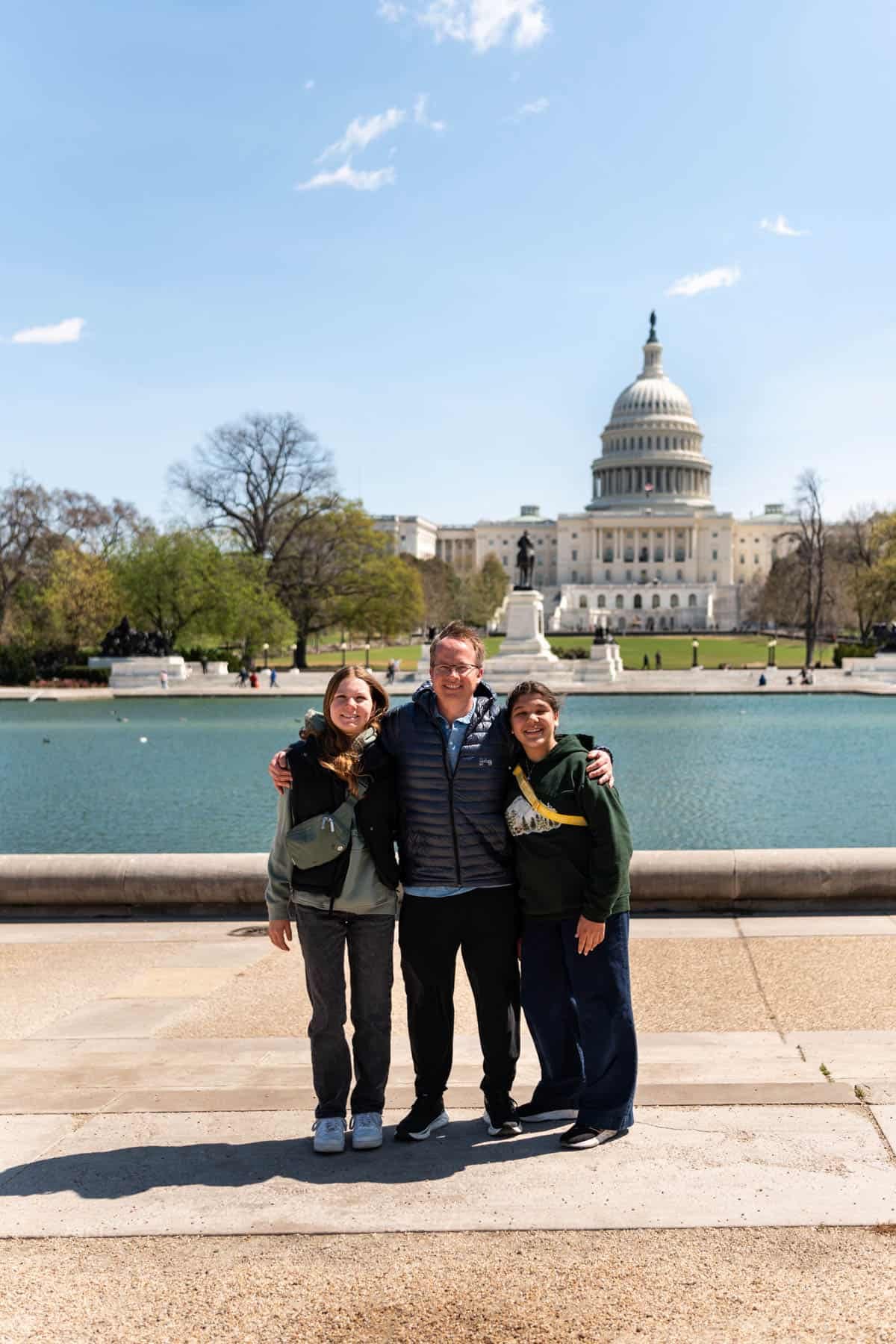 An image of a dad and two daughters in front of the capitol building in Washington D.C.