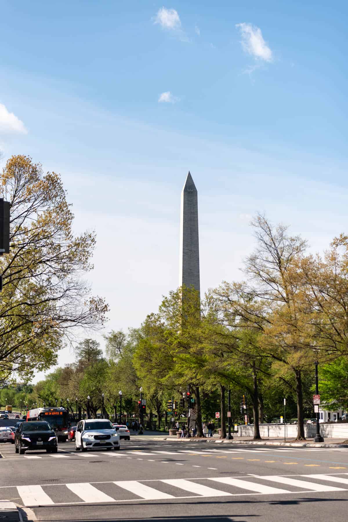 An image of the Washington Monument in Washington D.C. with cars on the street in front of it.