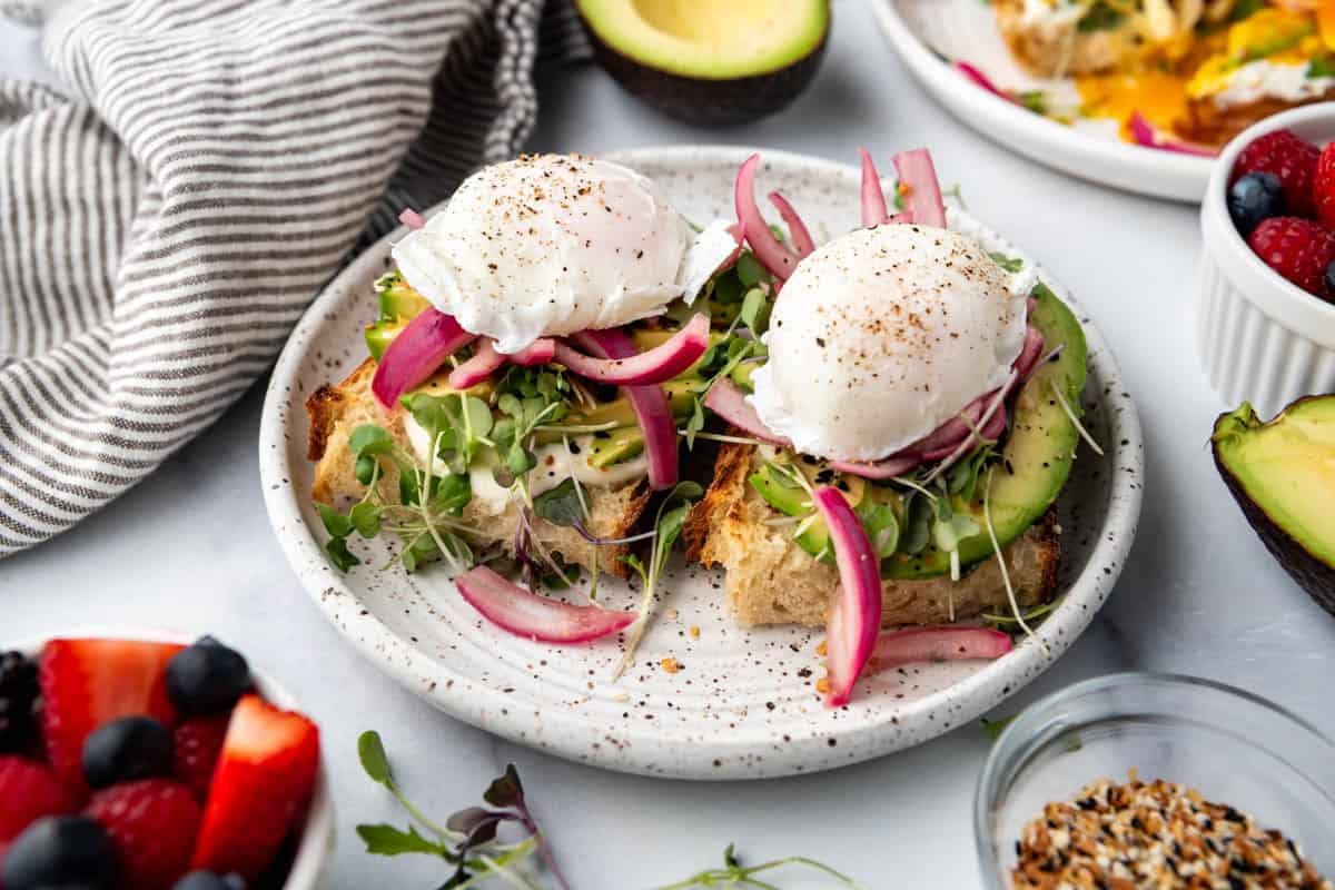 Two slices of sourdough toast with sliced avocado and poached eggs on top.