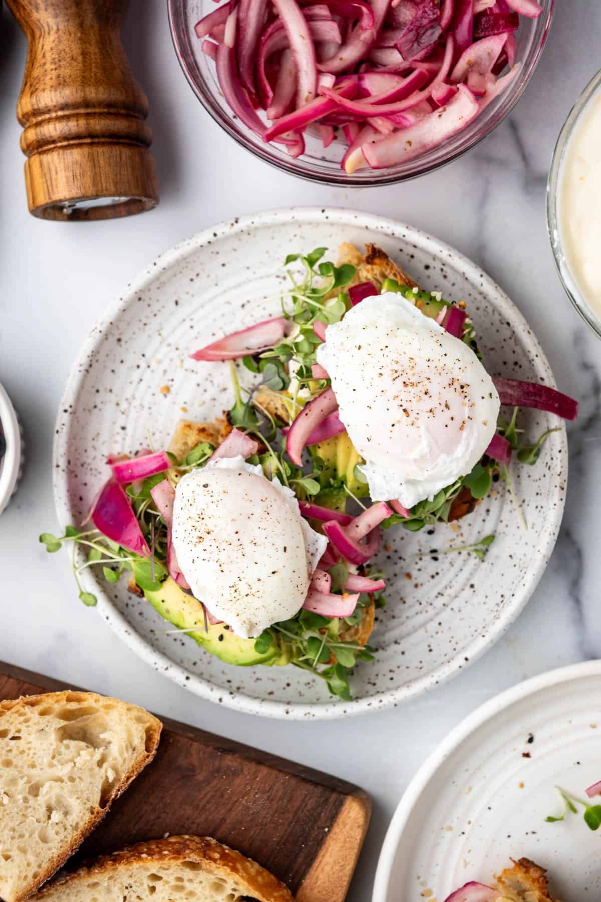 An overhead image of avocado toast on a plate with poached eggs on top.