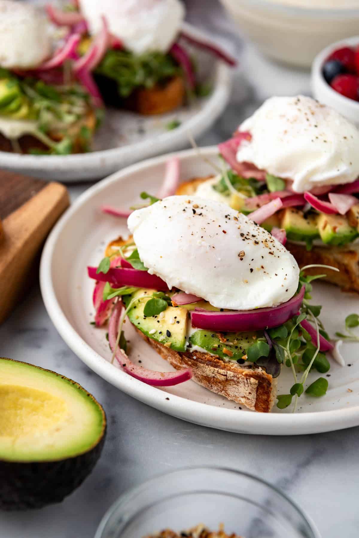 A side view of avocado toast piled with sliced avocado on top of a whipped honey orange ricotta spread.
