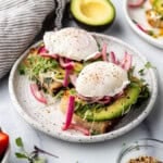 Two slices of sourdough toast with sliced avocado and poached eggs on top.