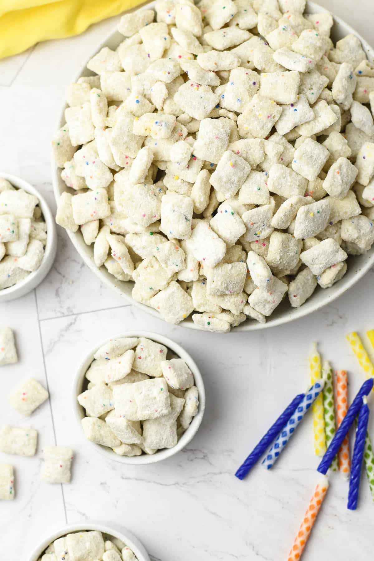 Bowls of cake batter puppy chow next to birthday candles.