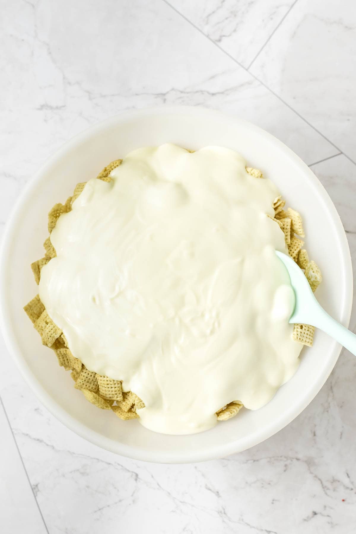 Adding melted white chocolate to rice chex.