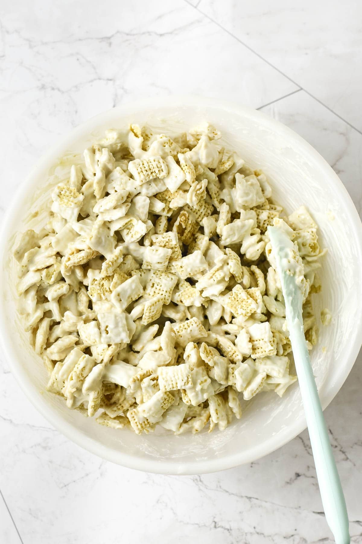 Covering rice Chex cereal in melted white chocolate.
