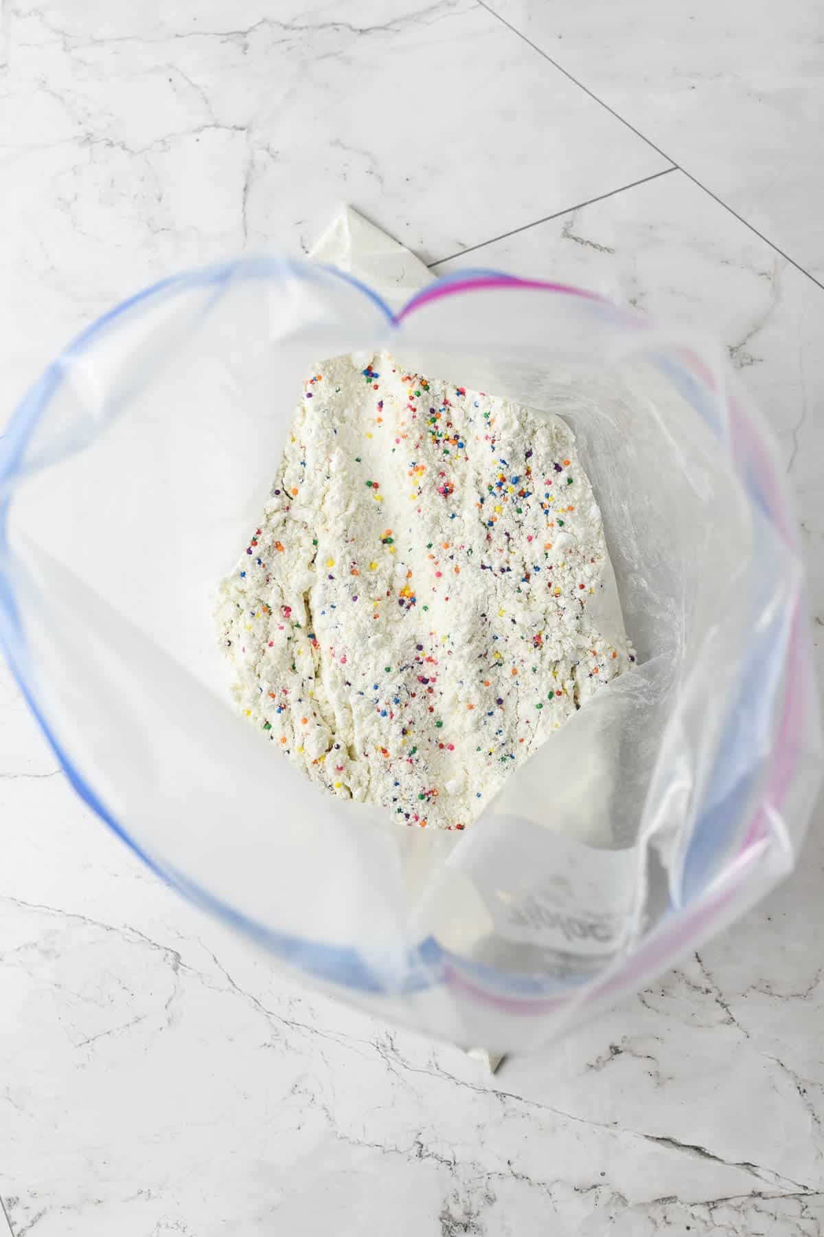 Adding heat treated funfetti cake mix to a ziploc bag.
