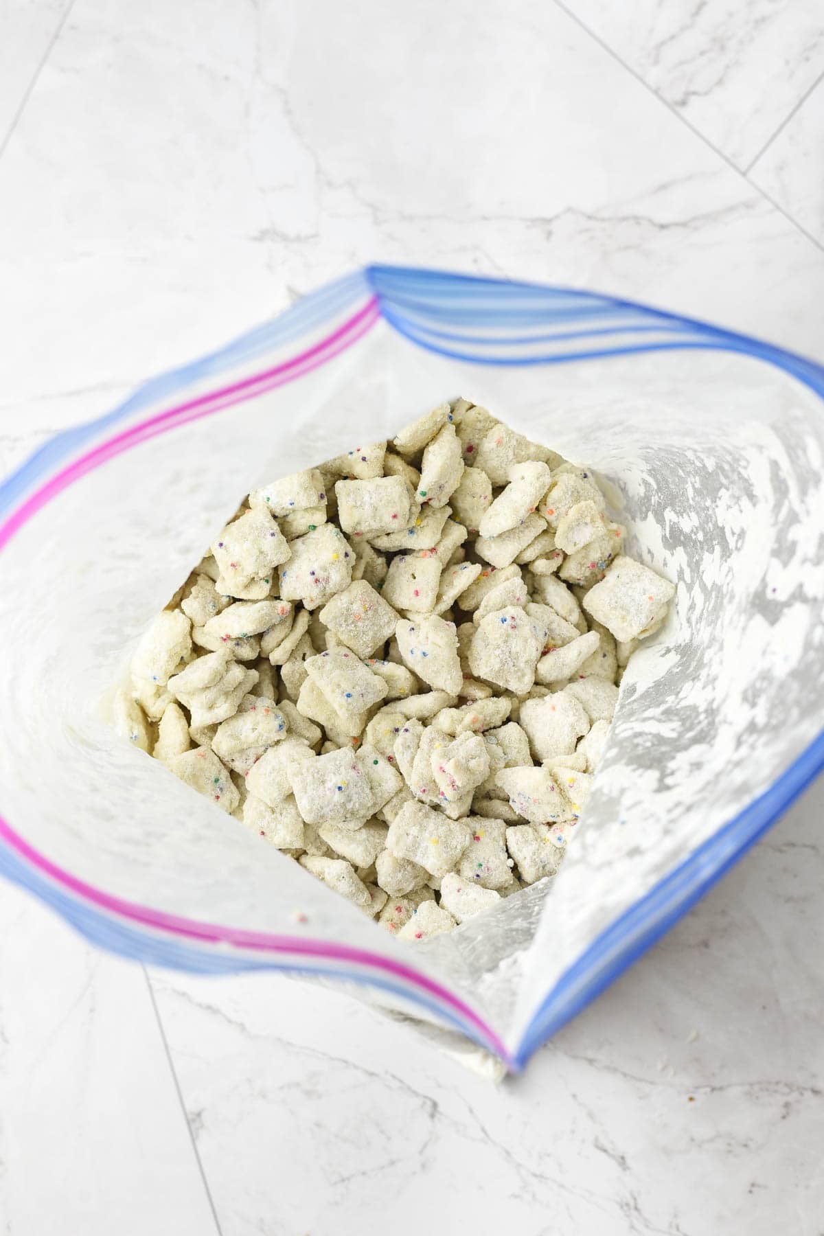 Cake batter puppy chow that has just been tossed to coat it in cake mix in a ziploc bag.