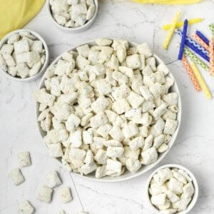 Bowls of cake batter puppy chow next to birthday candles.