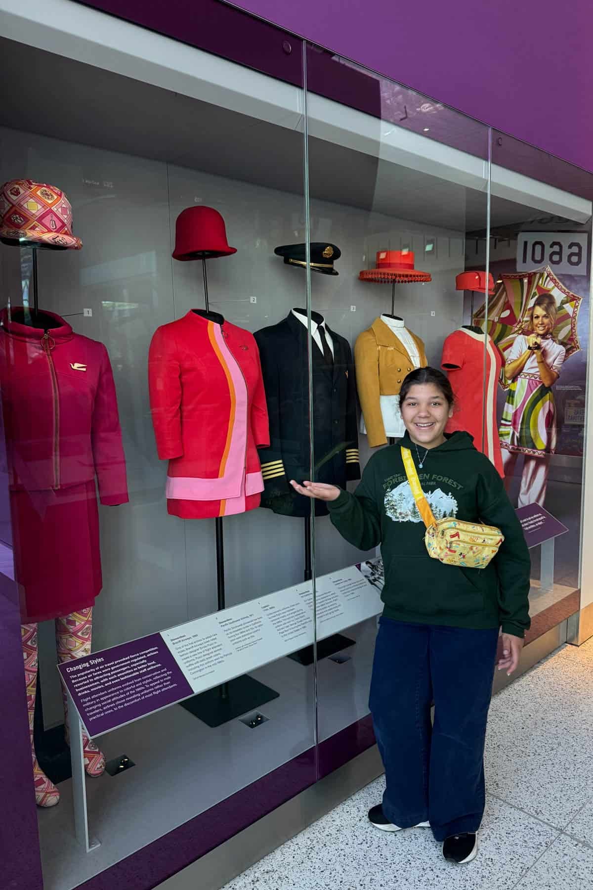 A girl in front of retro airline stewardess outfits at the Smithsonian.