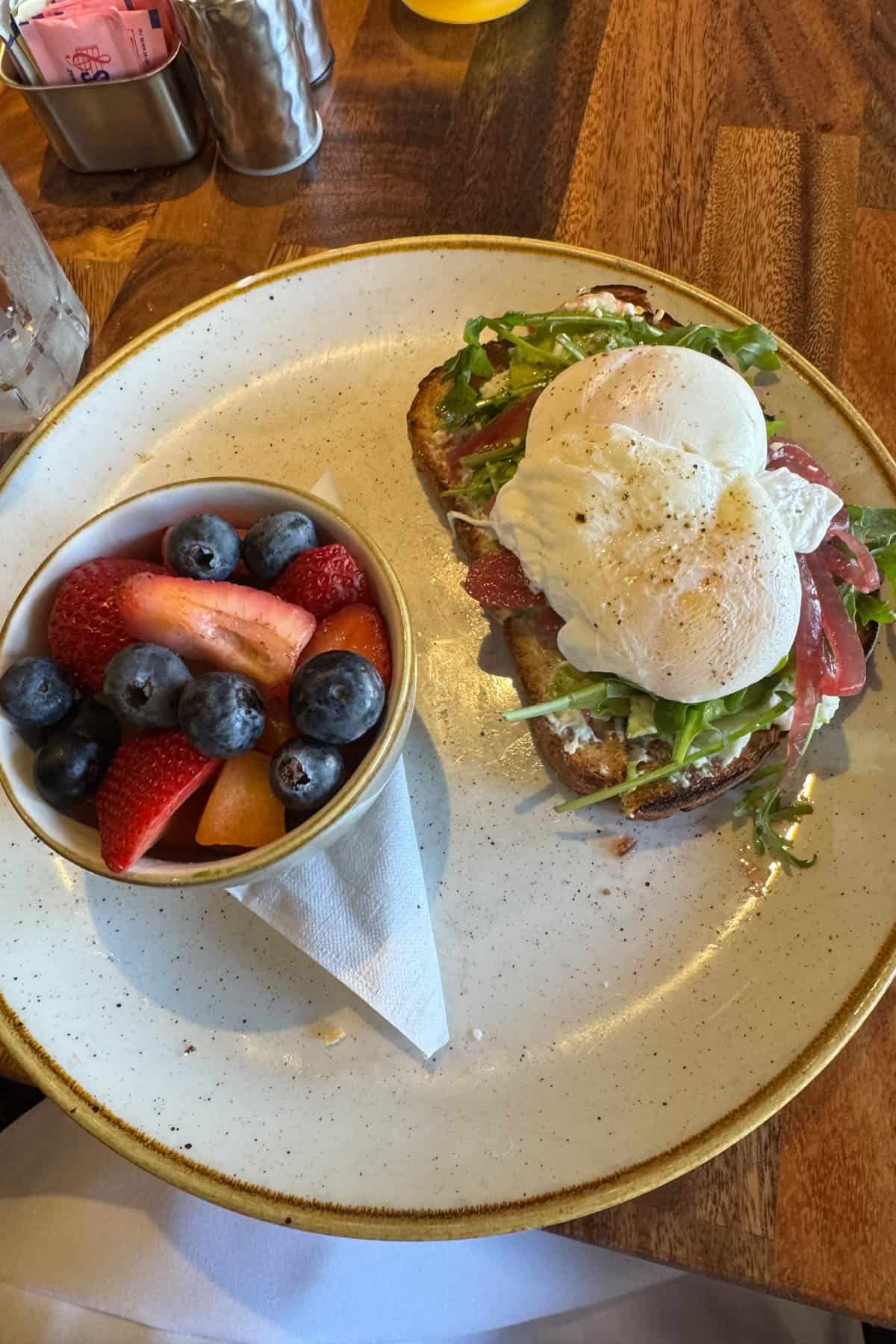 Avocado toast with poached eggs and fruit.