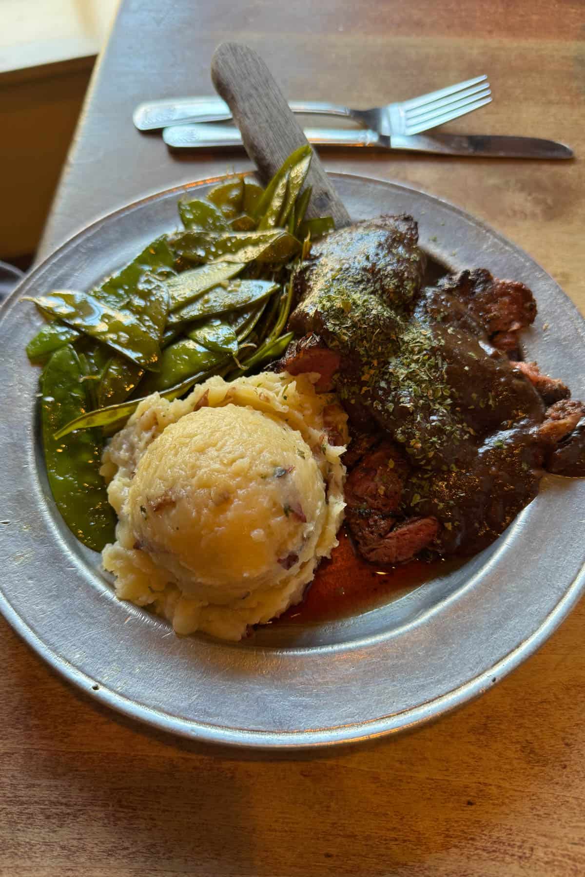 A plate of london broil, mashed potatoes, and vegetables.
