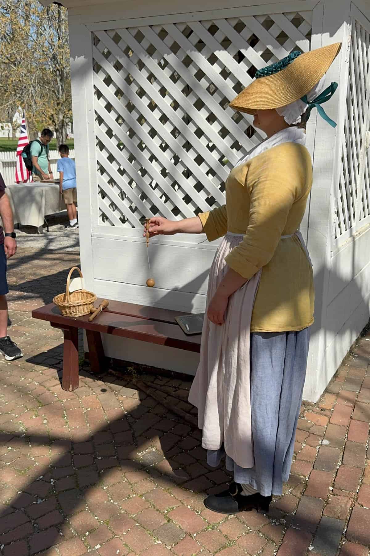 A woman dressed in colonial clothing demonstrating a game.