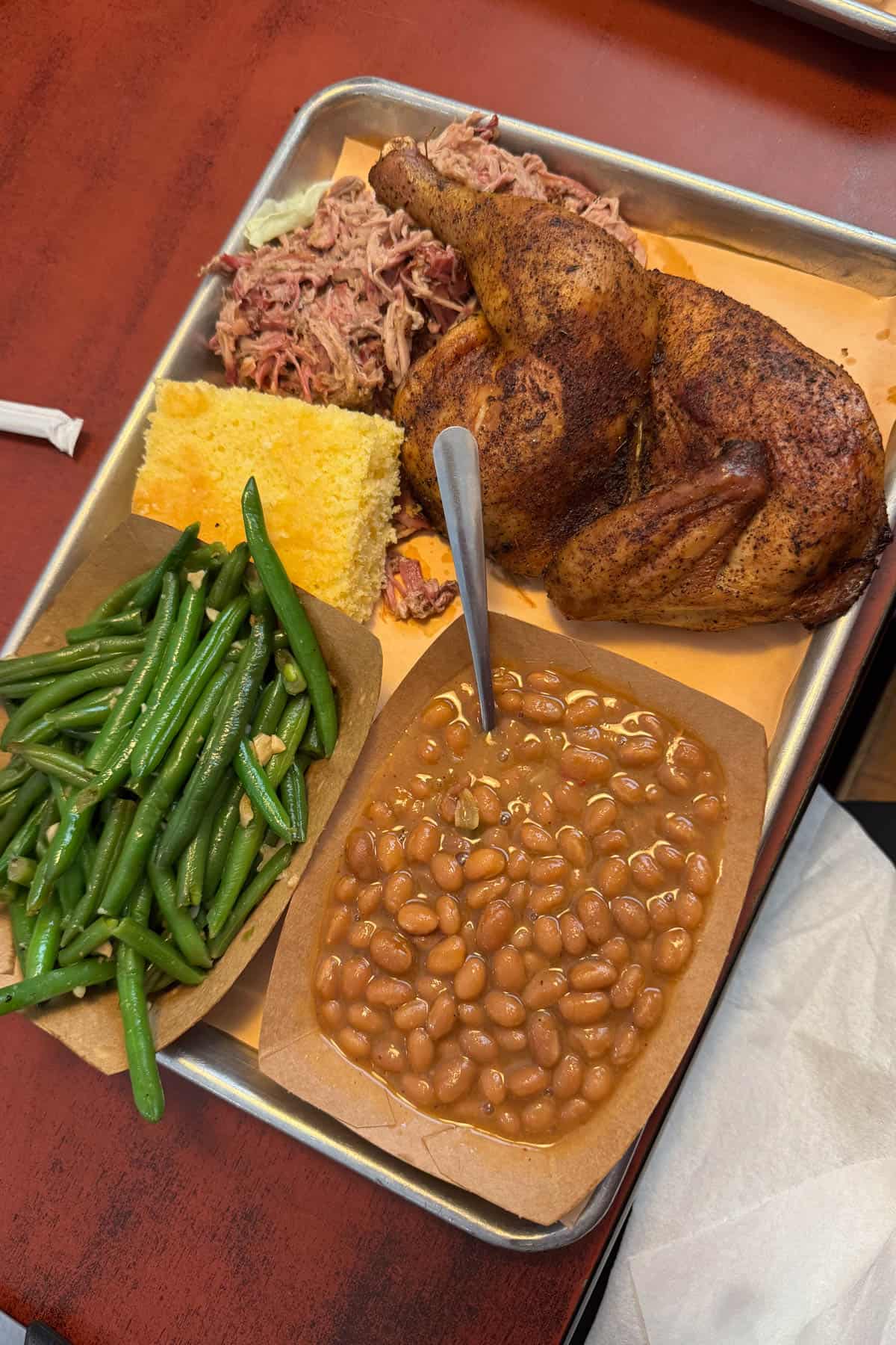 Smoked meats, beans, cornbread, and green beans on a tray.