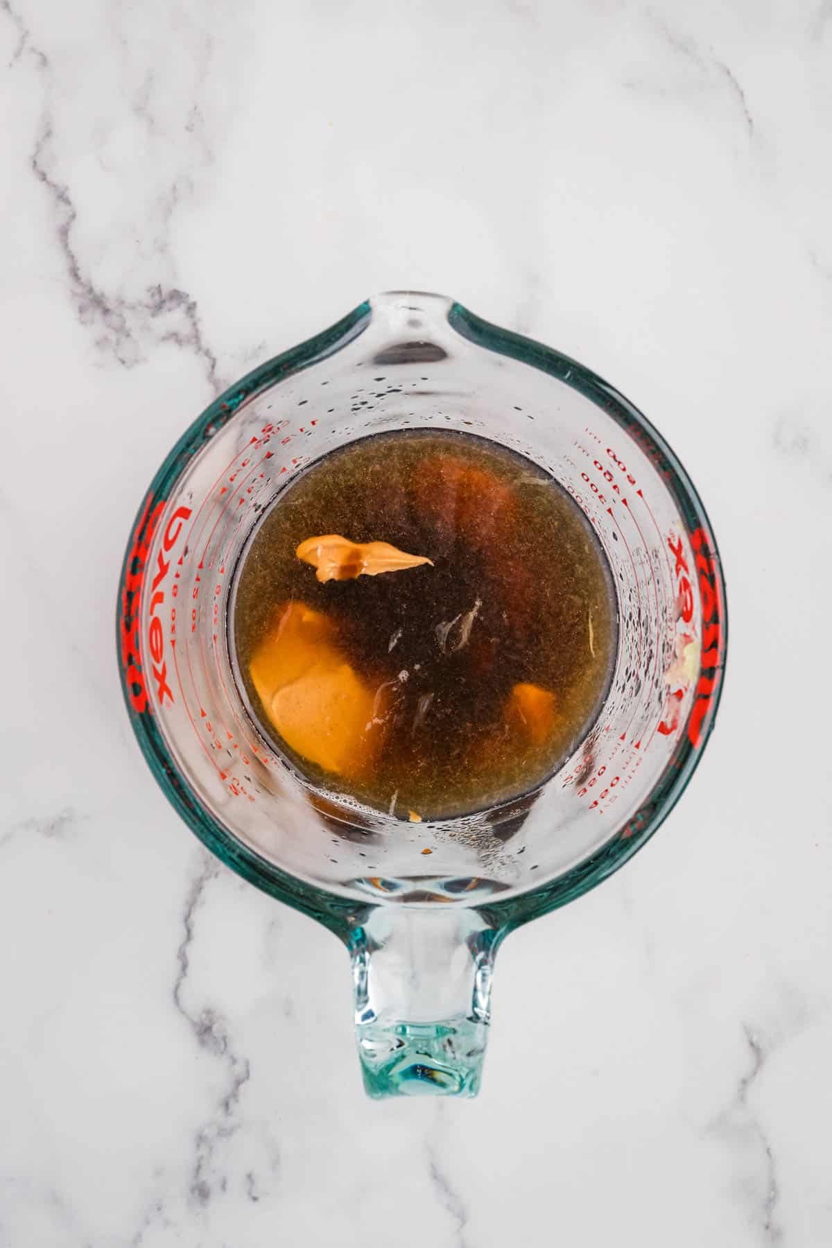 Combining ingredients in a glass mixing cup for the sauce for pad thai.