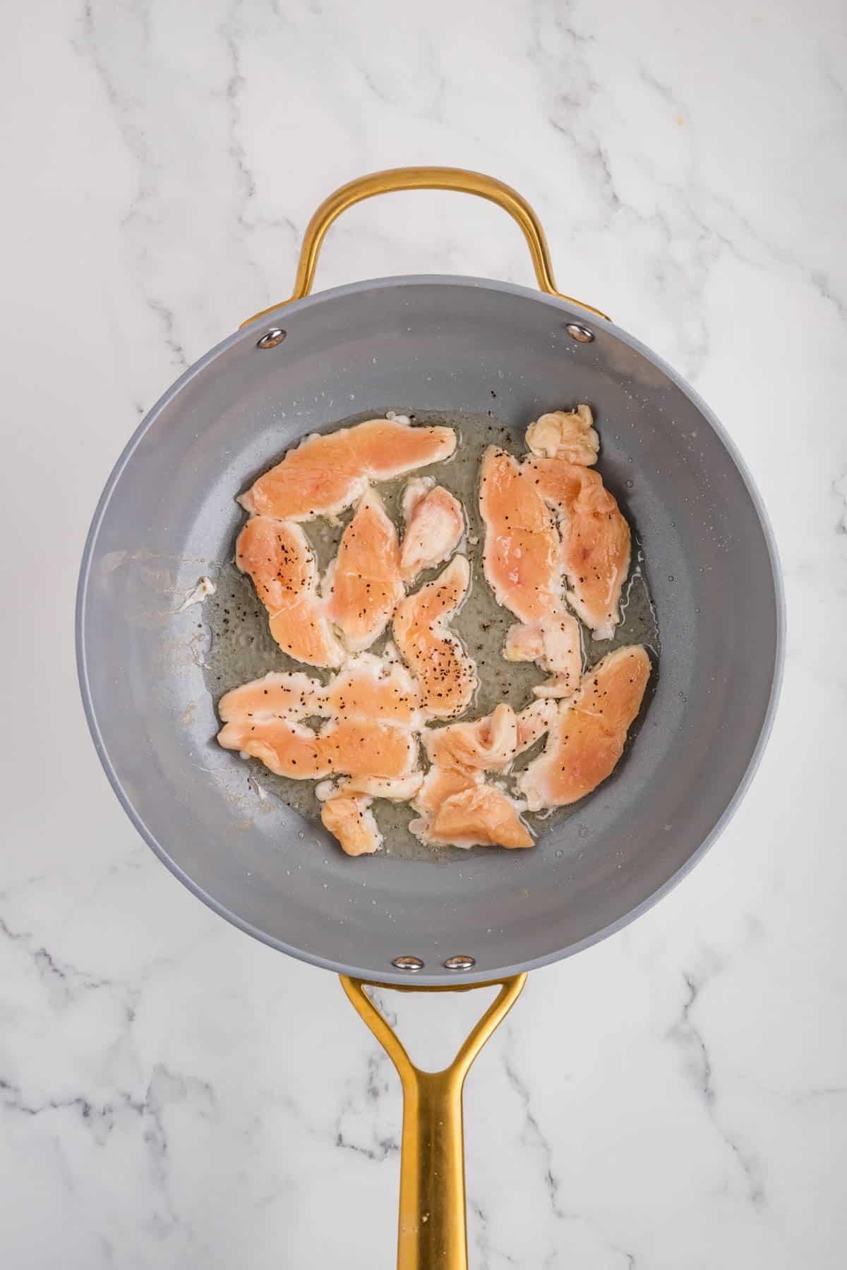 Chicken pieces being seared in a skillet.