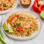 A plate of pad thai garnished with lime wedges.