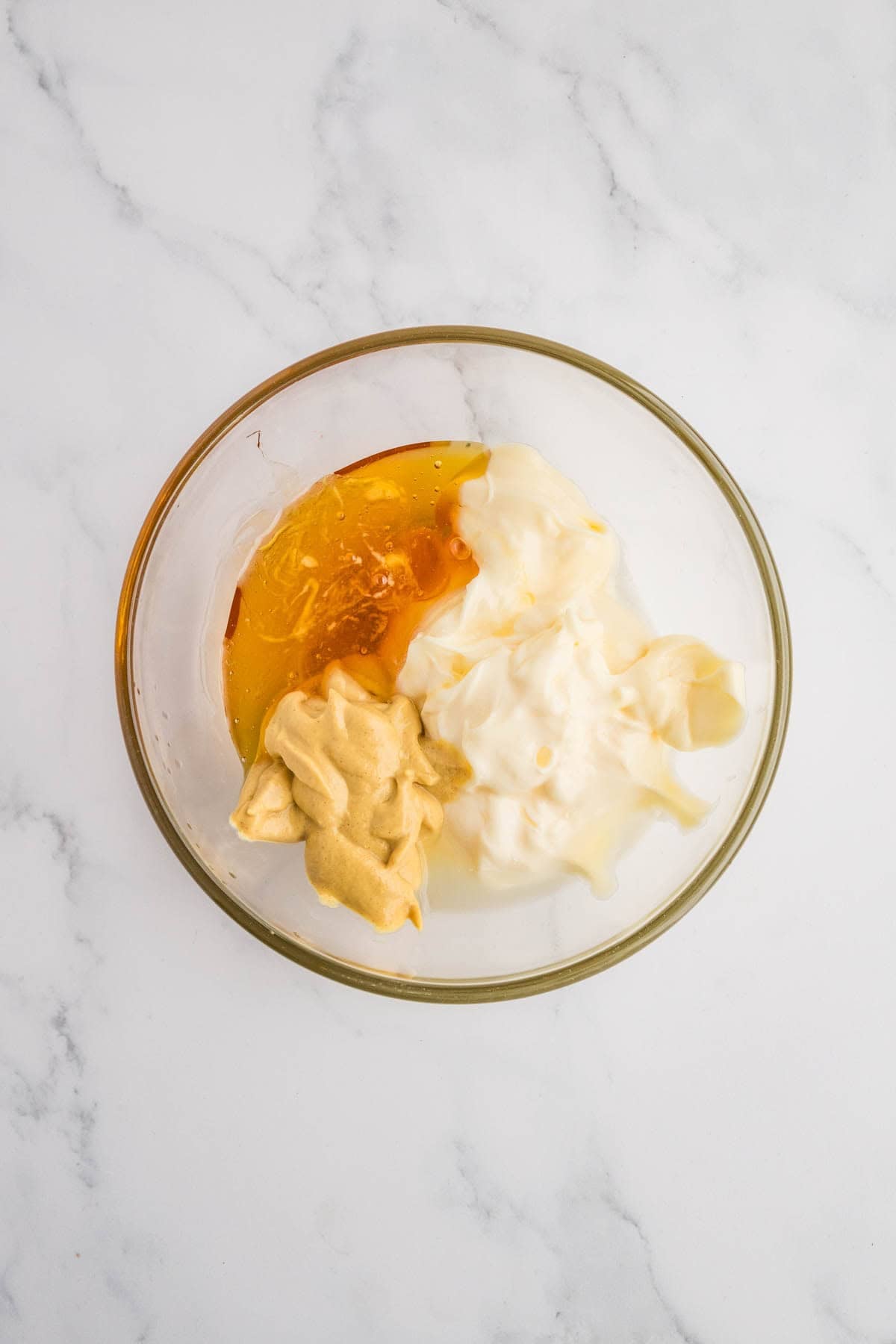 Combining mayo, mustard, and honey in a mixing bowl.