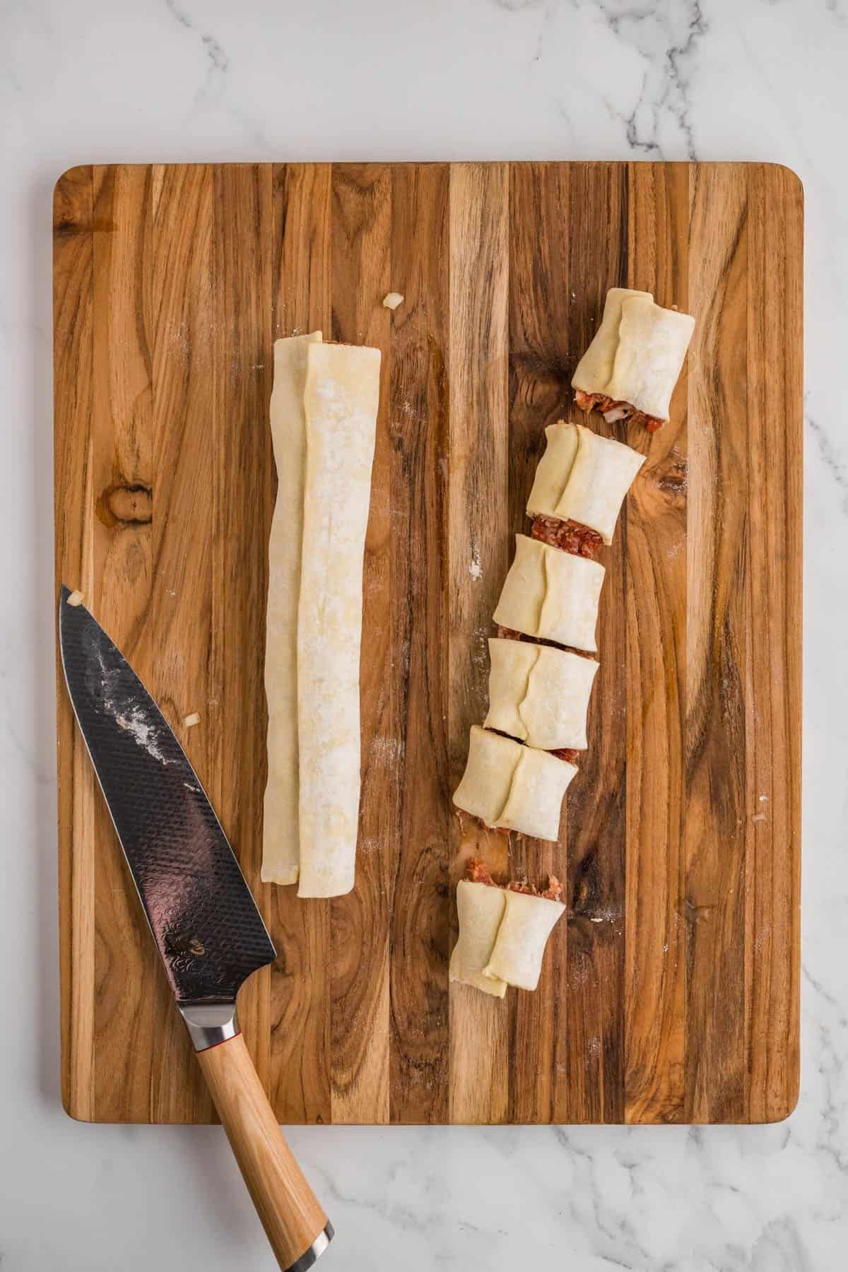 Two sausage rolls with one sliced into six pieces.