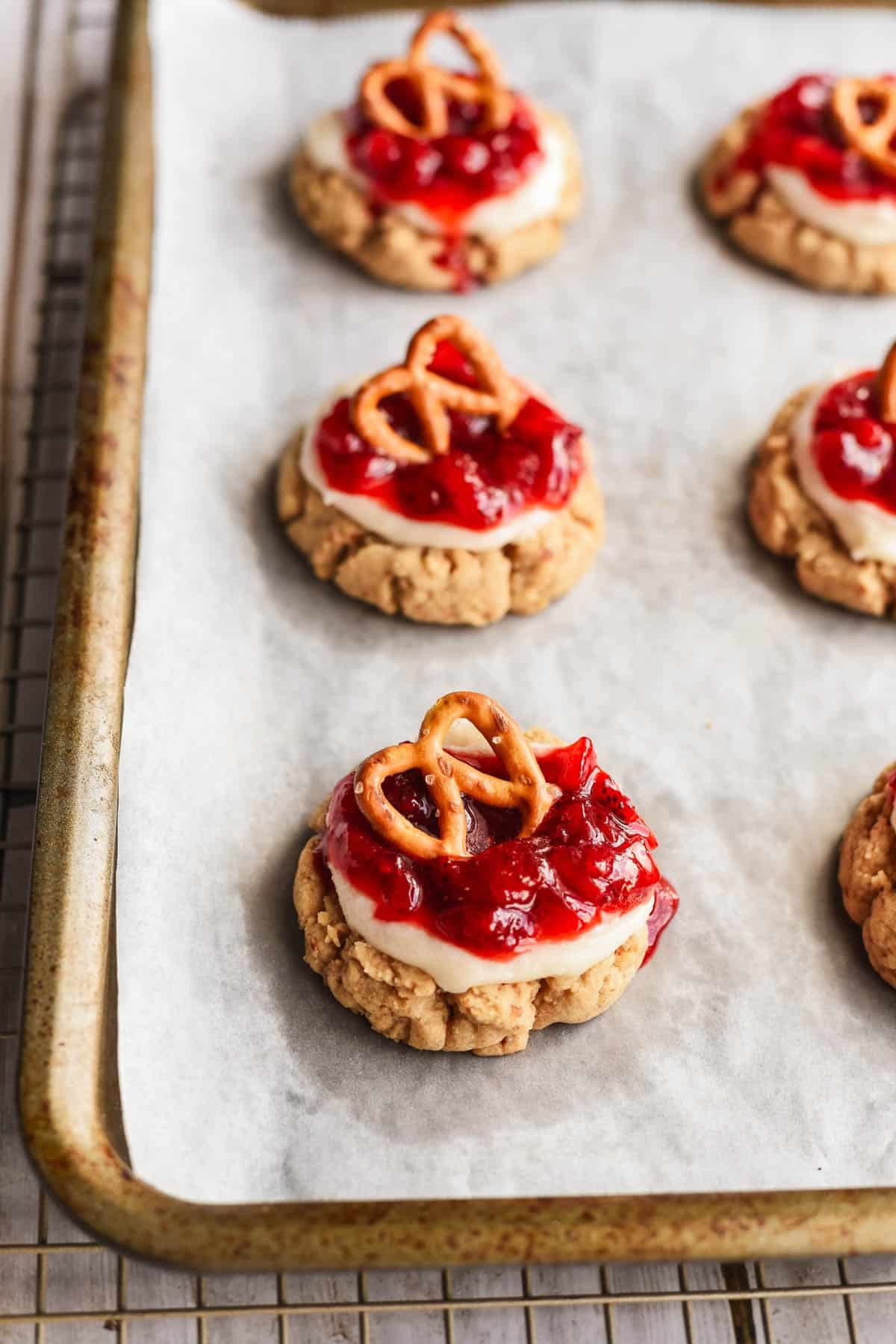 Finished strawberry pretzel cookies on a baking sheet lined with parchment paper.