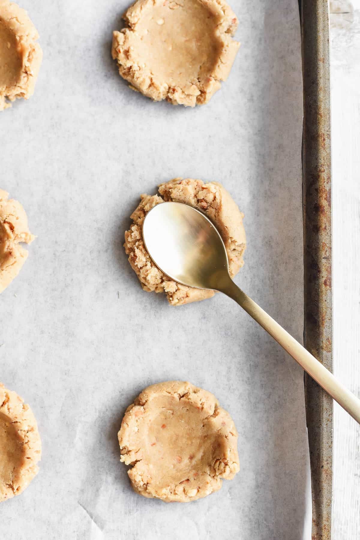 Using a spoon to create and indentation in cookie dough before baking.