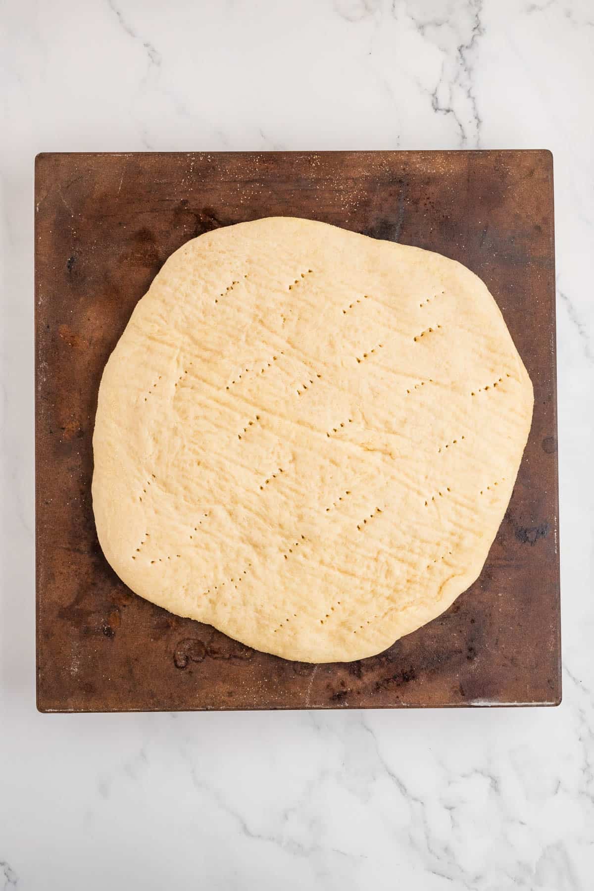Homemade pizza dough on a pizza stone.