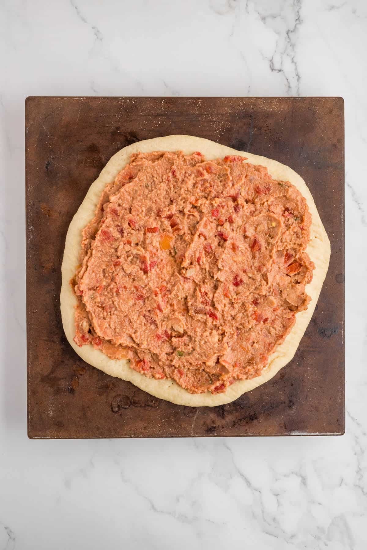 Adding refried beans to a pizza crust.