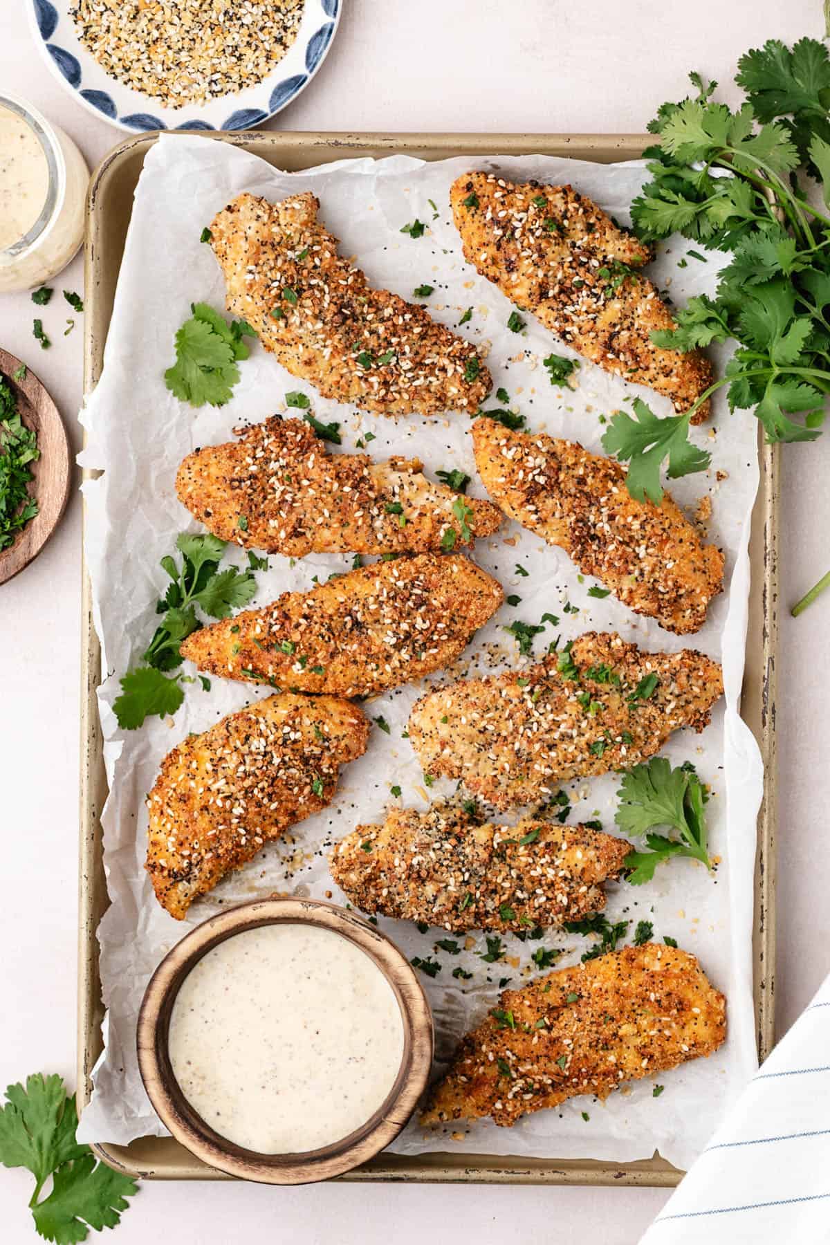 An overhead image of finished baked chicken tenders next to a bowl of honey mustard dip.