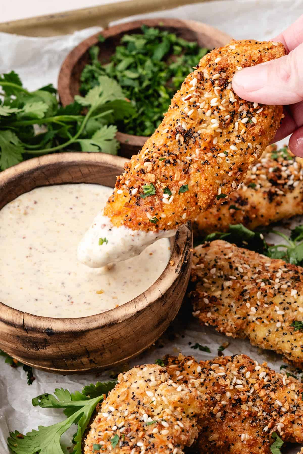 A baked chicken tender being dipped into a bowl of honey mustard sauce.