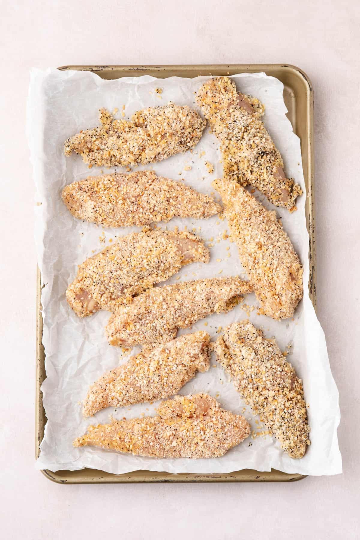 Breaded chicken tenders on a baking sheet.