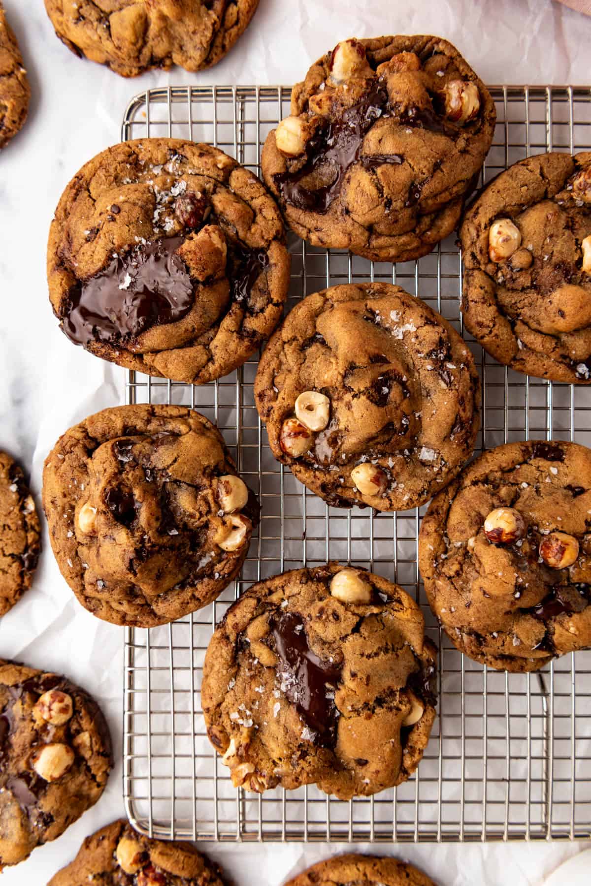 An overhead image of cookies with hazelnuts and chocolate on a wire rack.