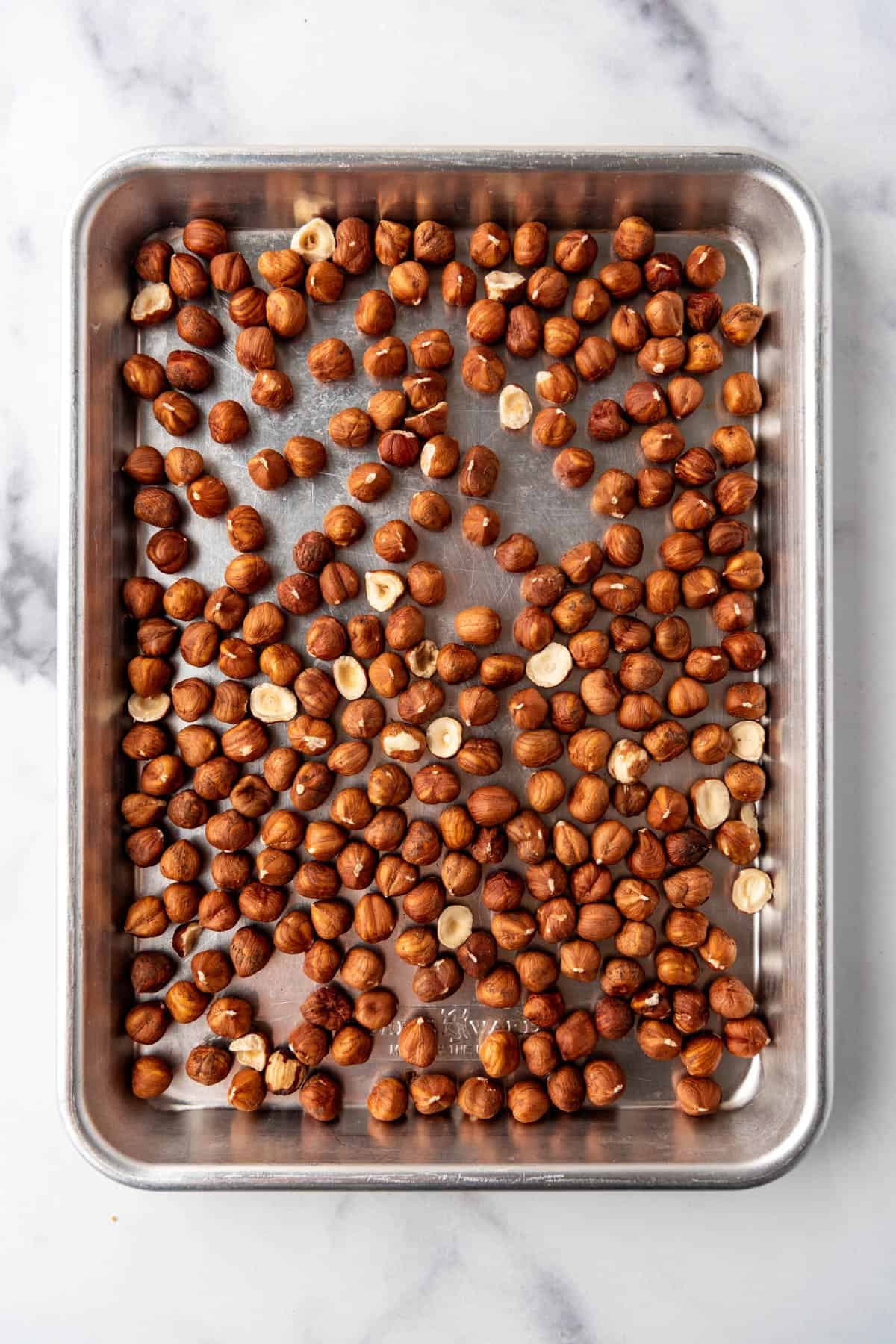 Whole hazelnuts on a baking sheet.