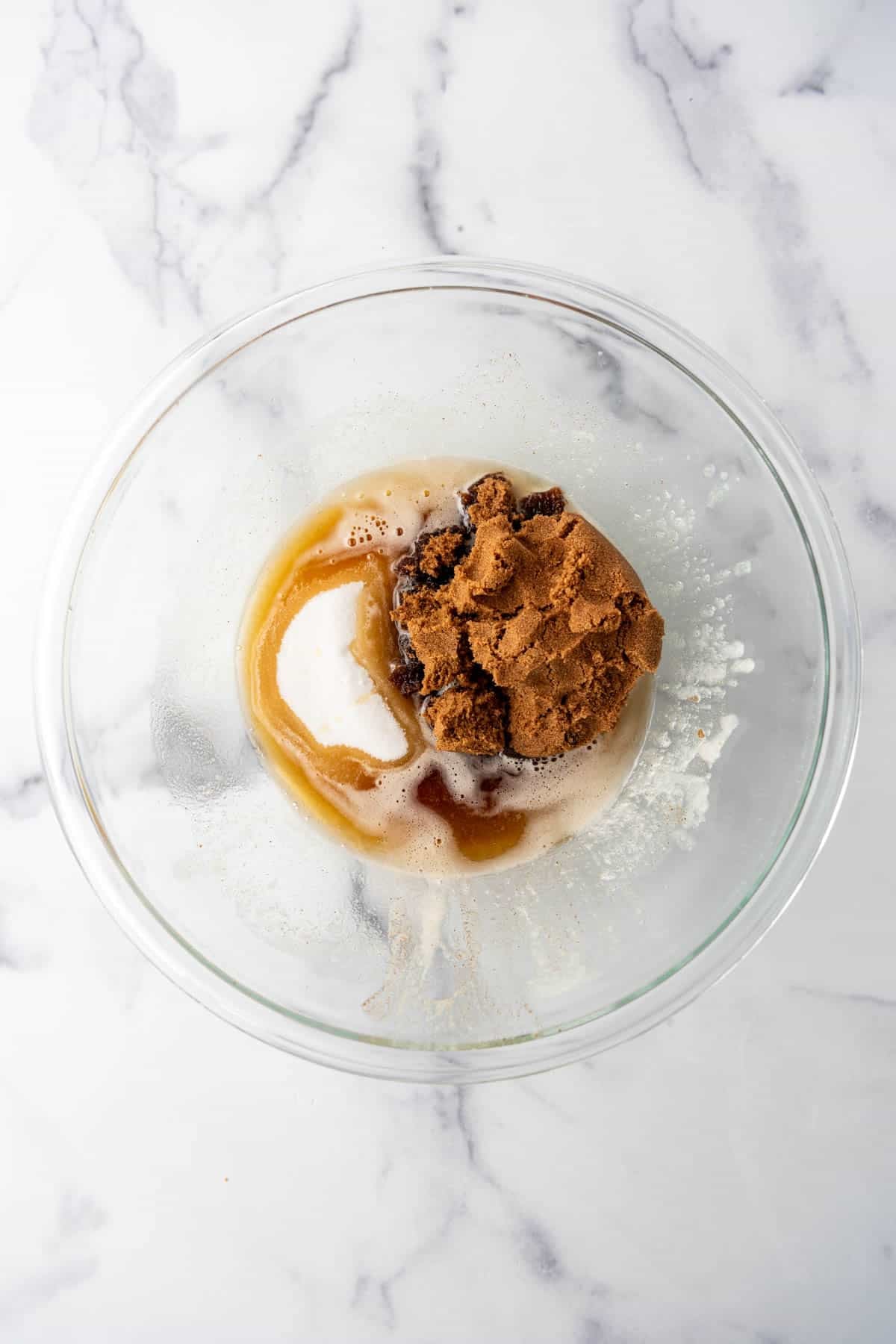 Adding sugars to brown butter in a large glass bowl.