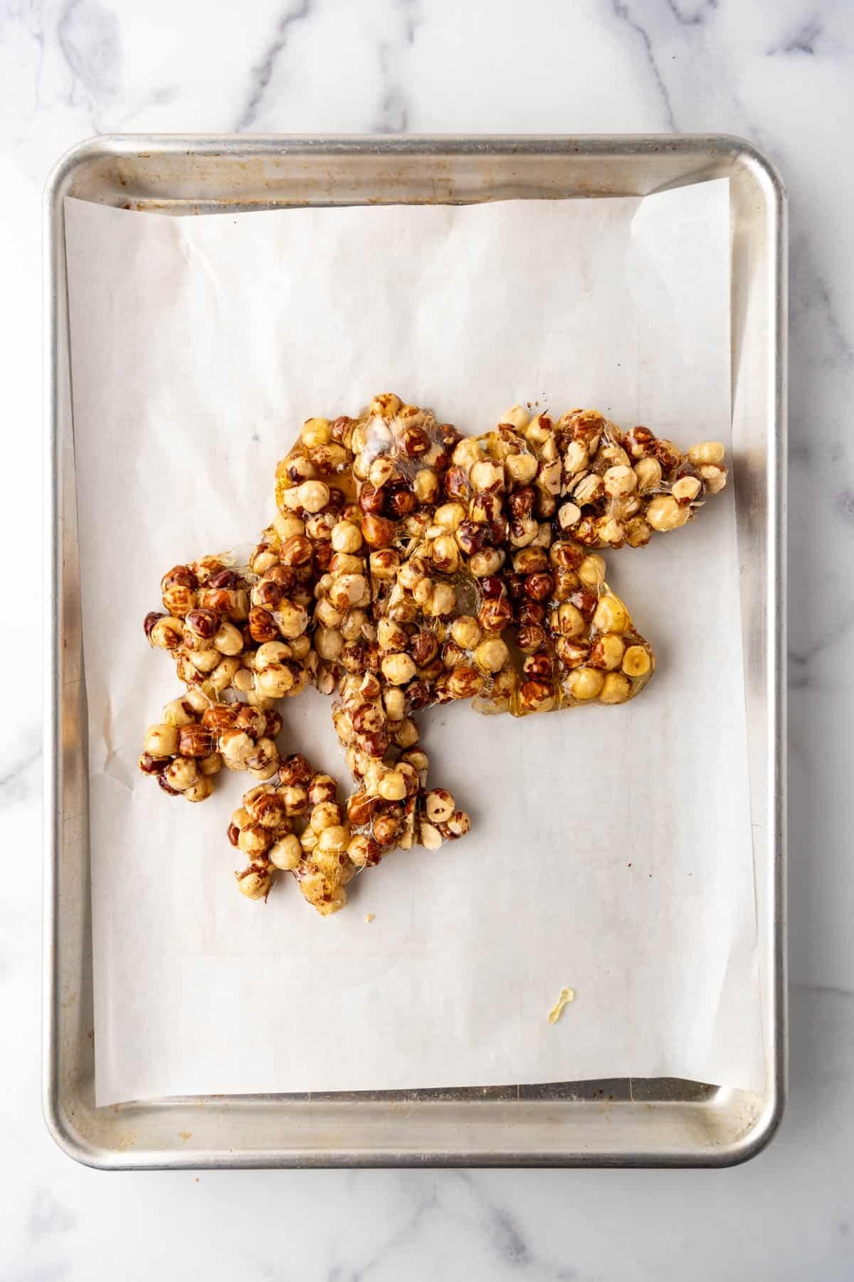 Candied hazelnuts on a baking sheet lined with parchment paper.