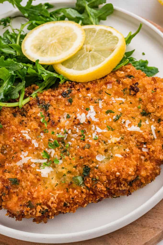 An image of chicken milanese sprinkled with parmesan and parsley.