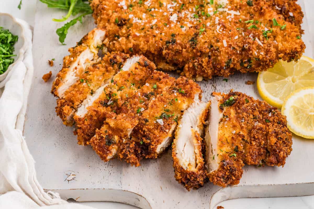 Sliced chicken milanese on a cutting board.