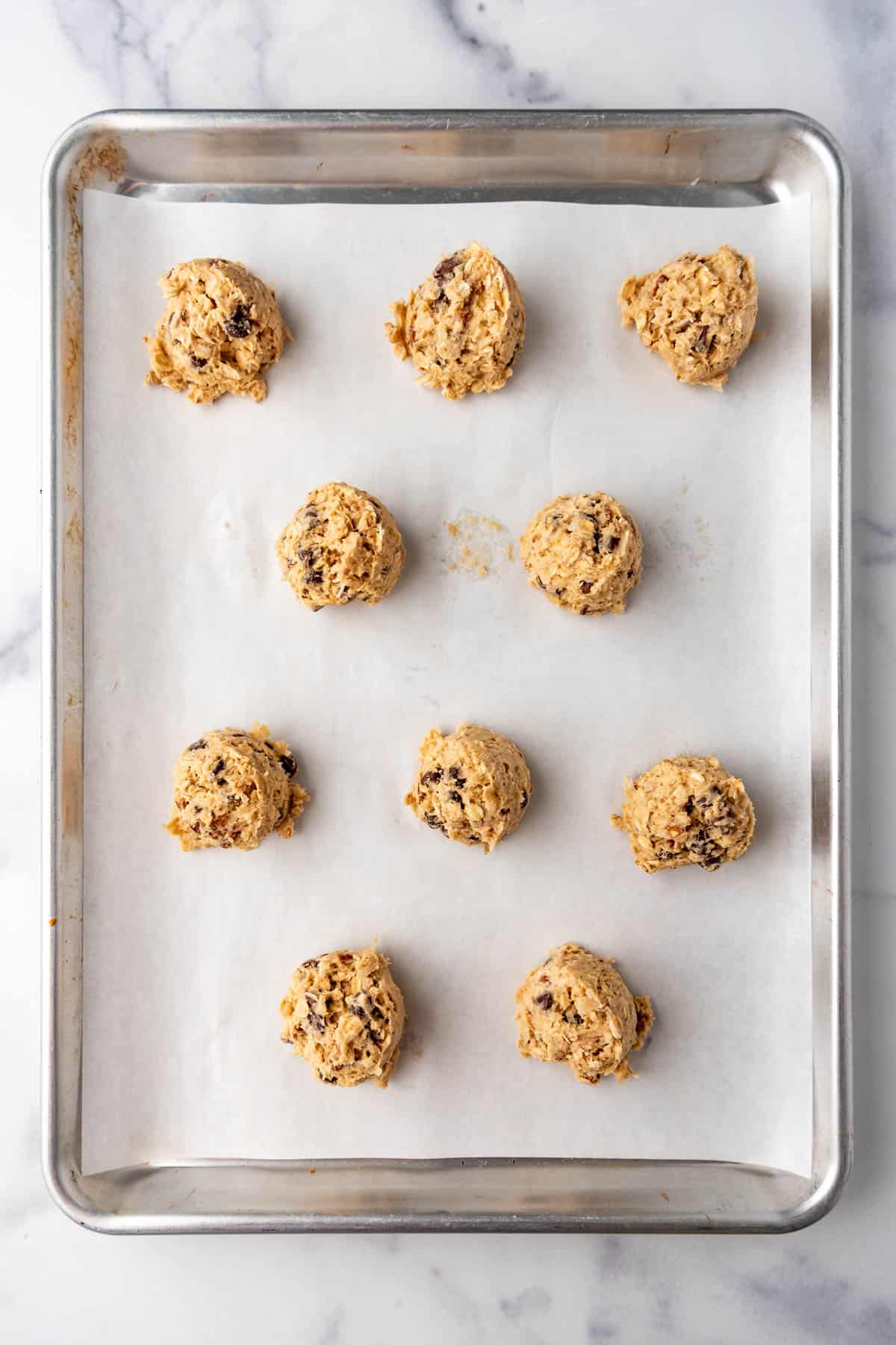 Balls of cookie dough on a baking sheet lined with parchment paper.