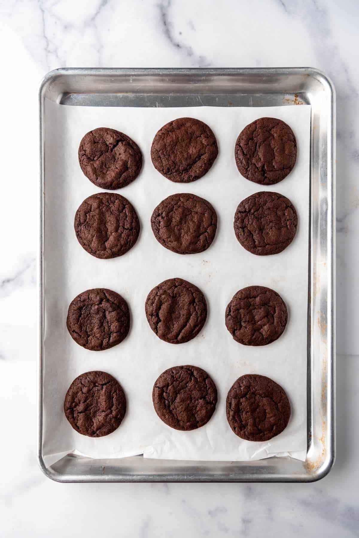 Baked chocolate cookies on a baking sheet lined with parchment paper.