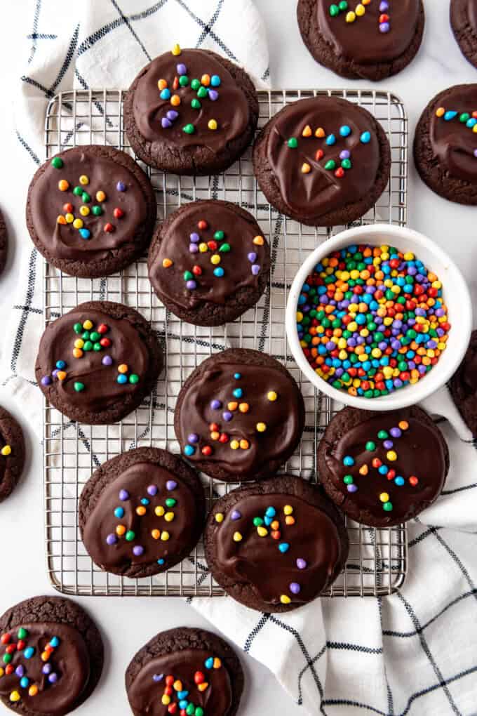 An overhead image of copycat Crumbl cosmic brownie cookies next to a bowl of rainbow chips.