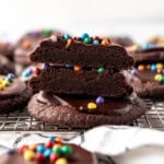 An image of crumbl copycat cosmic brownie cookies with one sliced in half and stacked on top of each other.