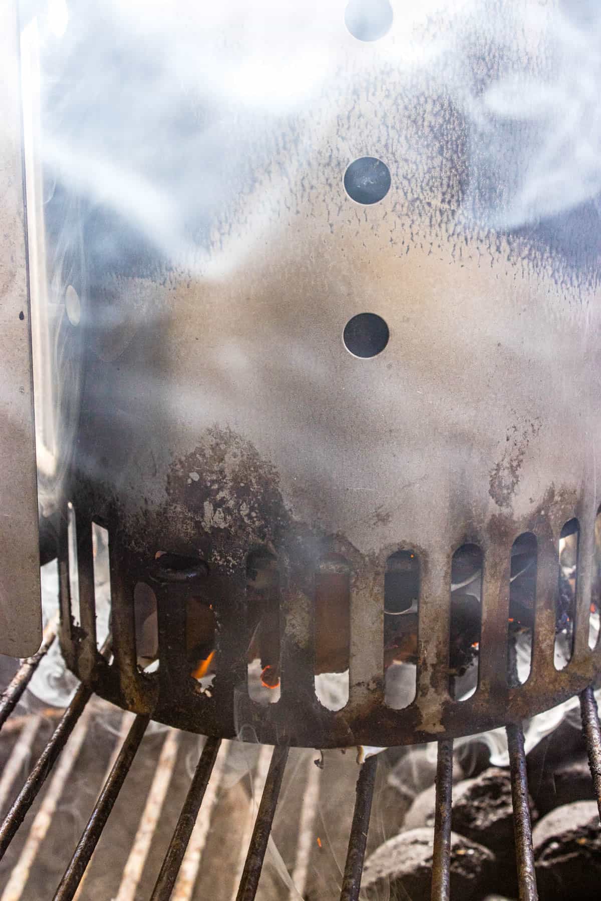 A flame at the bottom of a charcoal chimney starter.