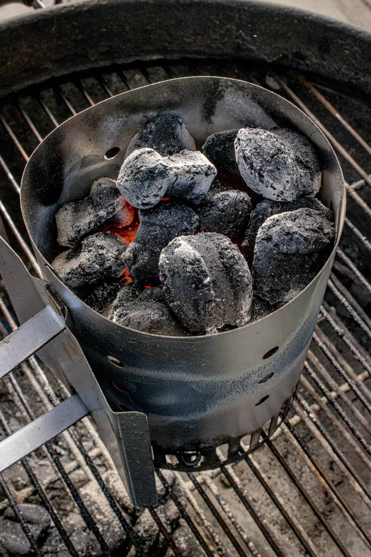 An image of charcoal in a chimney on a grill.