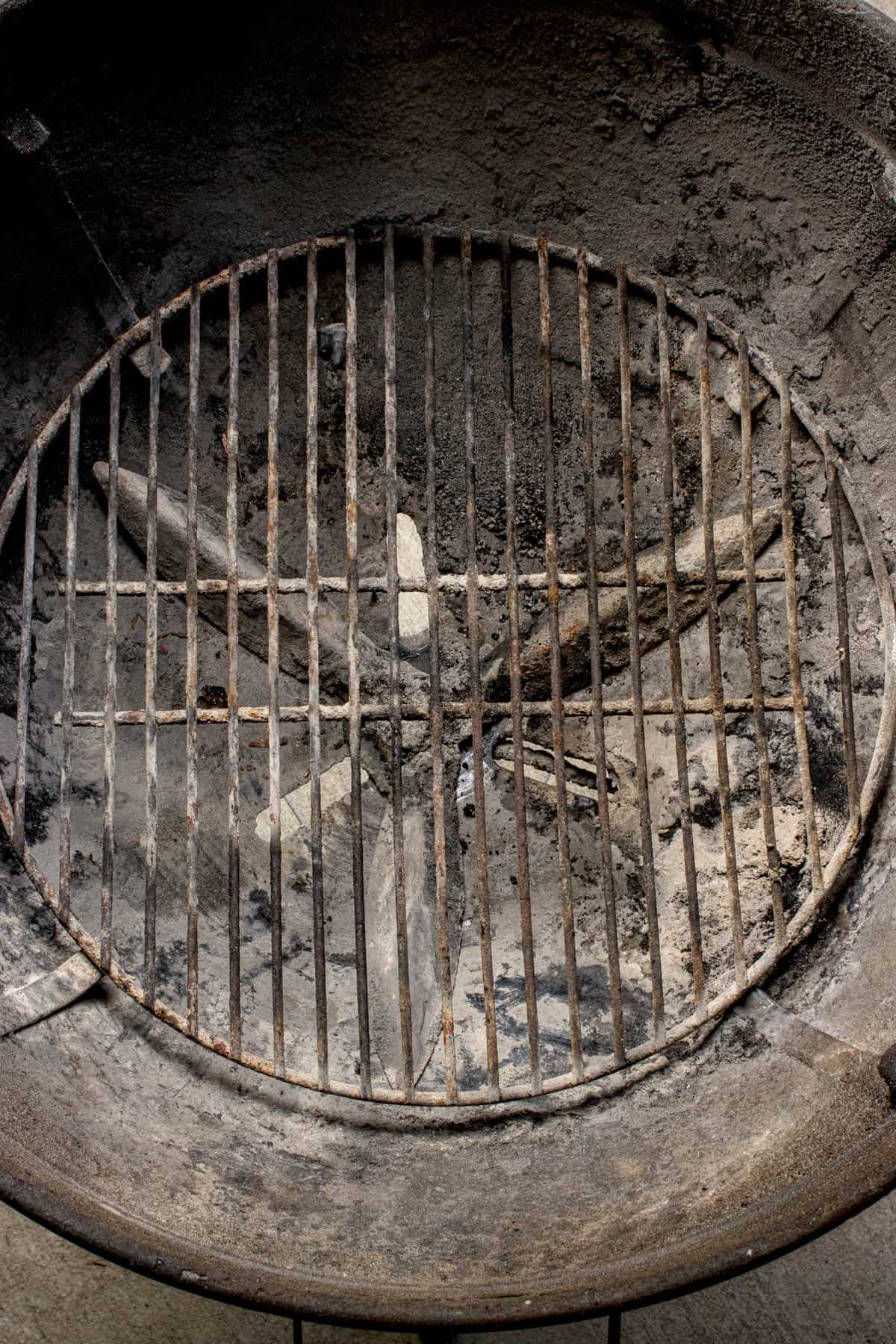 An image of the bottom grate on a charcoal grill with vents open.