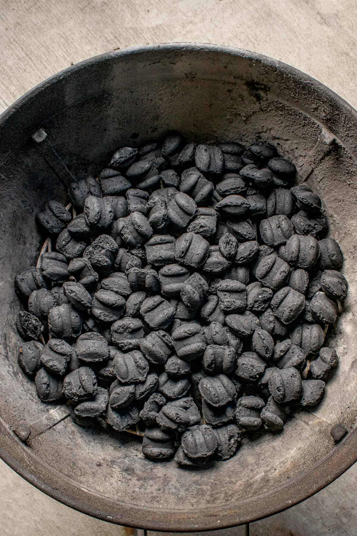 An image of the bottom of a charcoal grill completely covered in unlit charcoal.