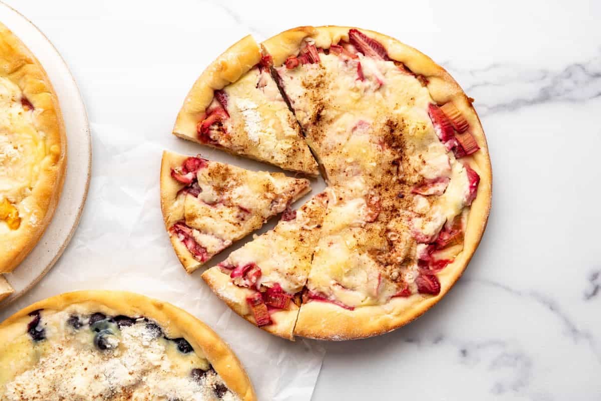 An overhead image of a partially sliced strawberry rhubarb kuchen.