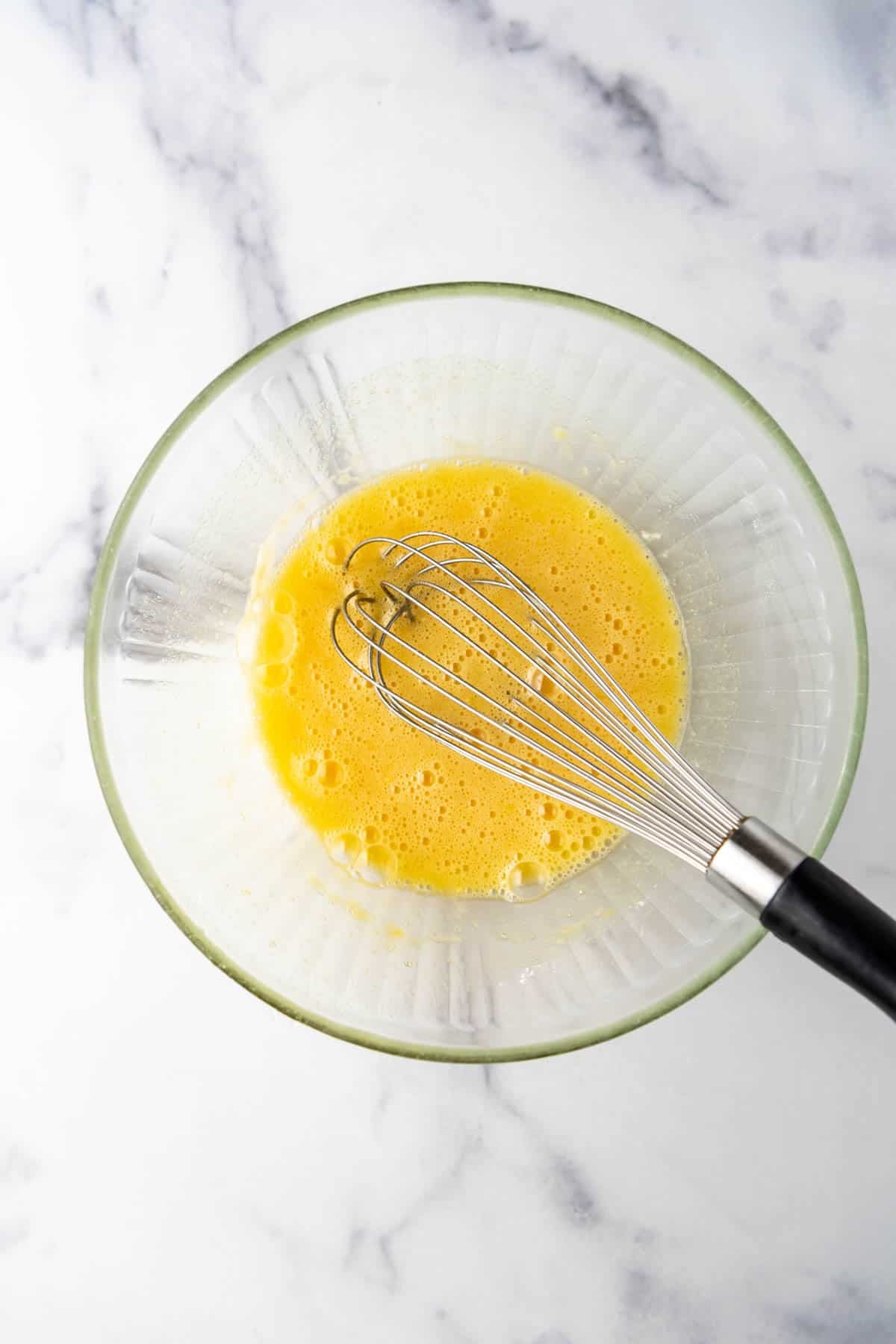 An image of eggs, sugar, and flour whisked together in a mixing bwol.