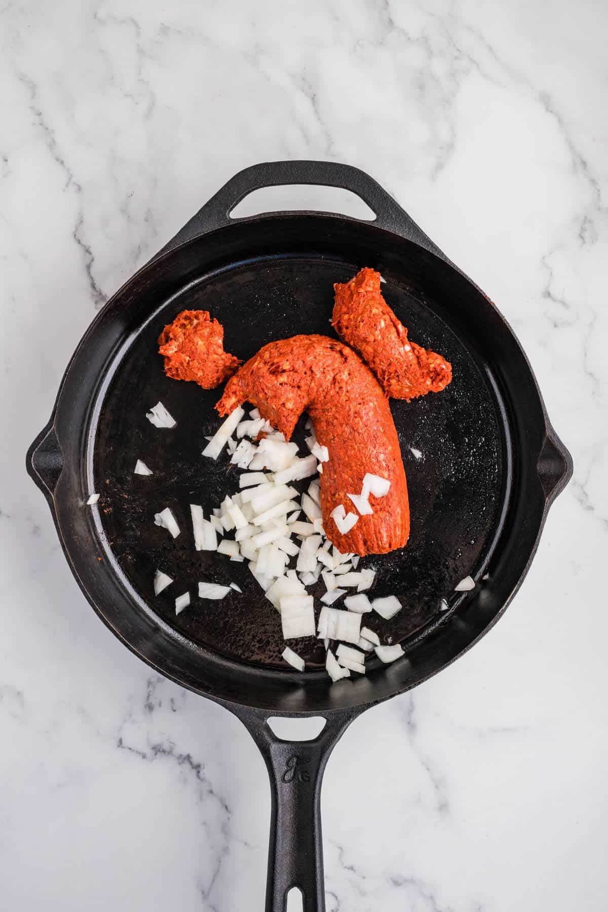 Chorizo sausage and onions in a large skillet.