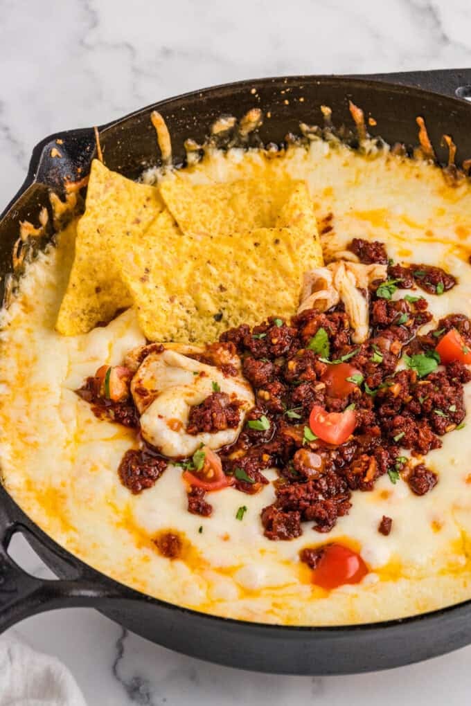 Tortilla chips in a pan of queso fundido.