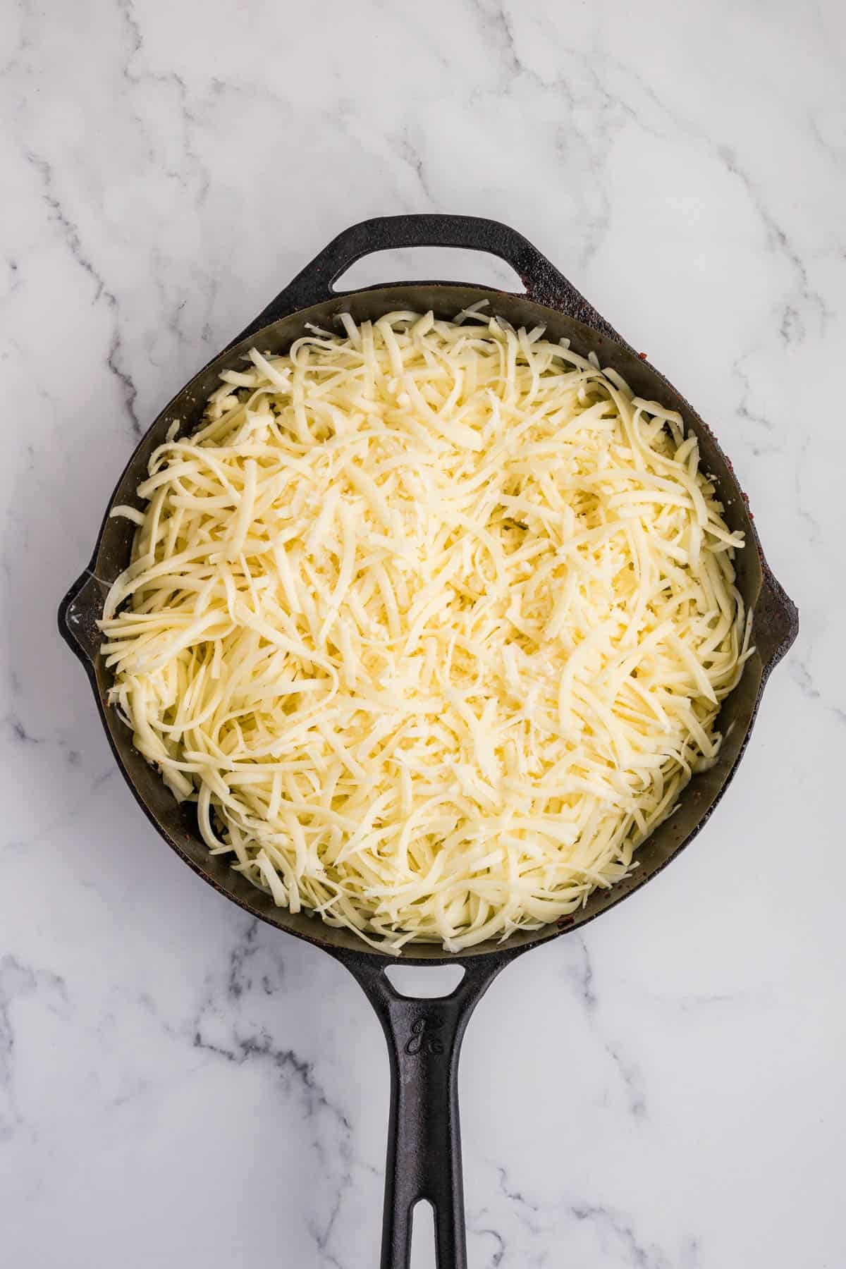 Shredded oaxaca cheese in a skillet.